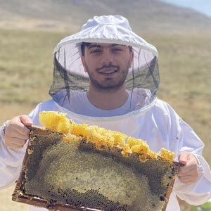 عسلی قلعه، بنیان‌گذار آهوتا، در حال بازدید از کندو با قاب موم عسل